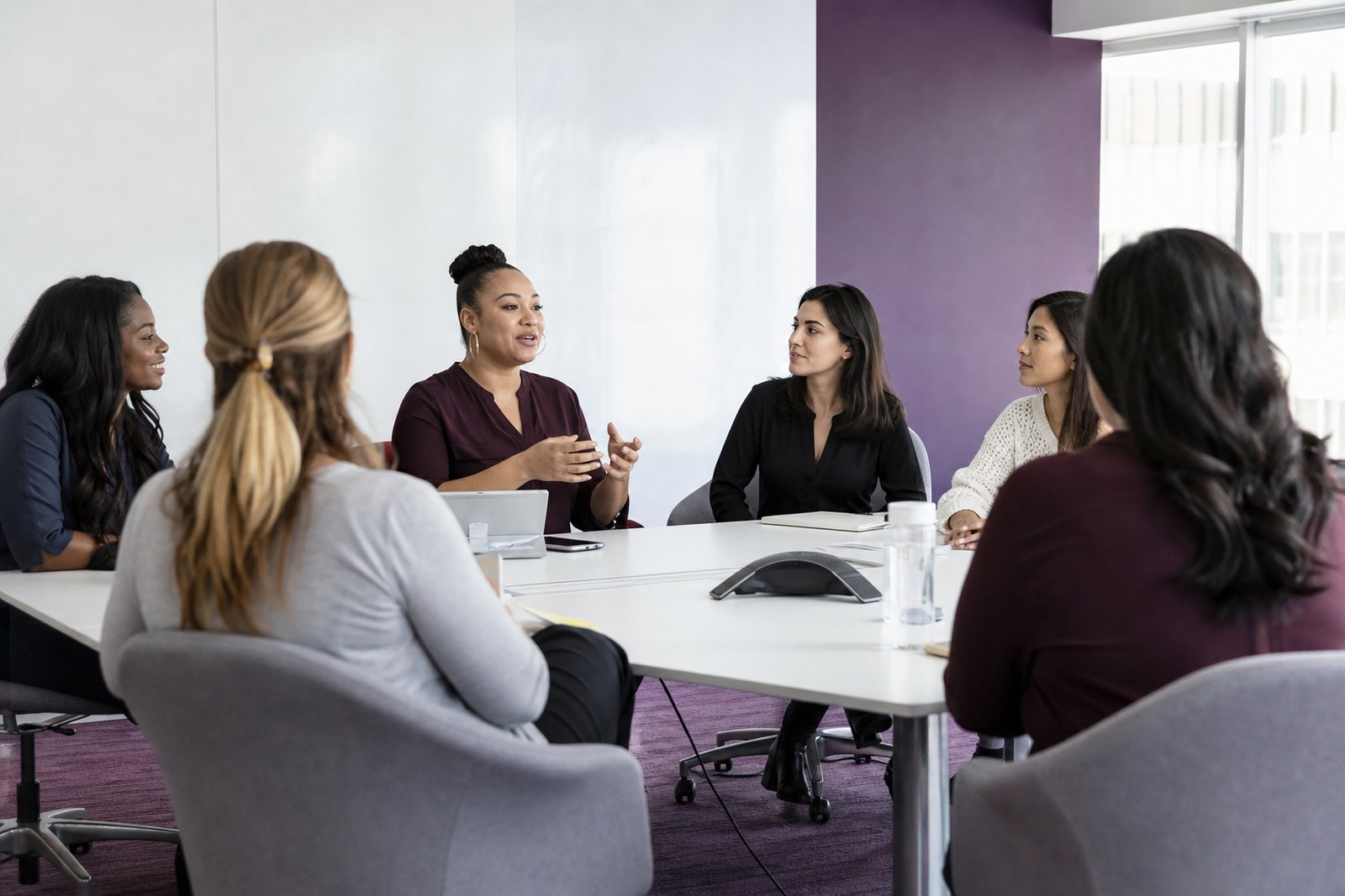 Members of a women's employee resource group seated around a conference table during a chapter meeting in daylight